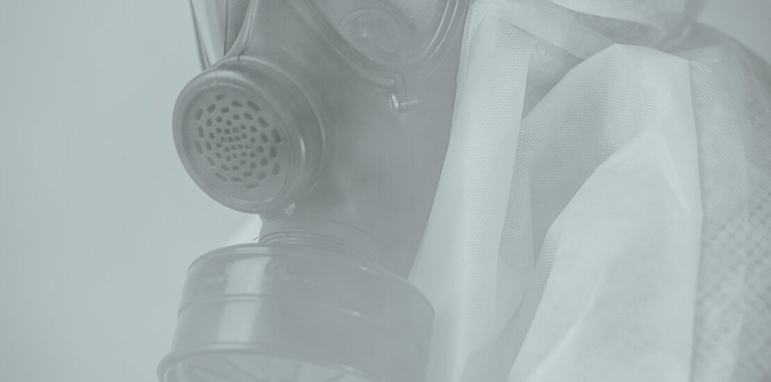Worker wearing protective coveralls and a full-face respirator for asbestos safety.